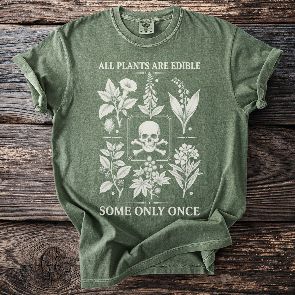 Green t-shirt with skull and crossbones and botanical illustrations. "ALL PLANTS ARE EDIBLE SOME ONLY ONCE."
