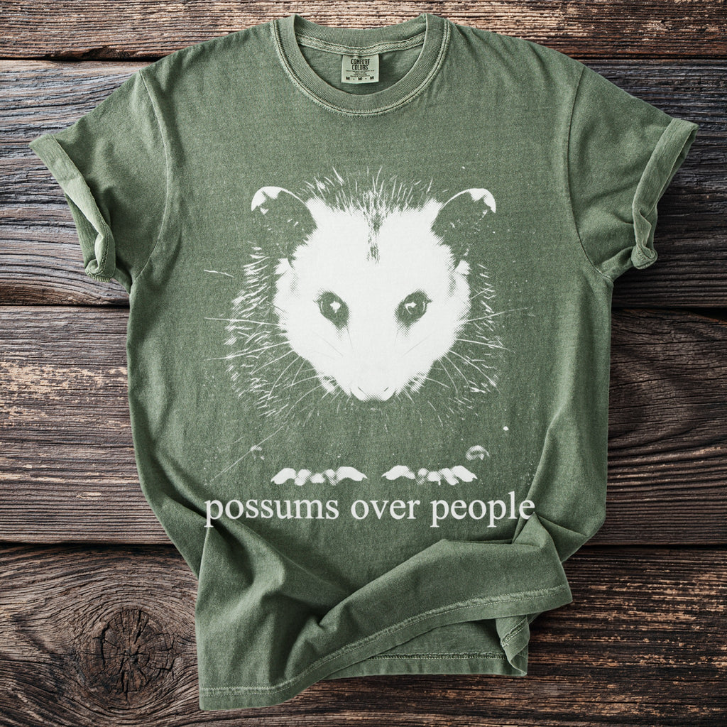 Green t-shirt with possum graphic and text "possums over people".