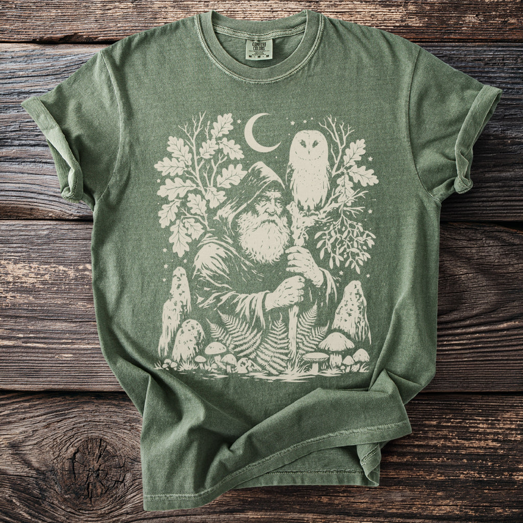 Green t-shirt with a white graphic of a hooded wizard, owl, moon, trees, and mushrooms.
