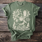 Green t-shirt with a white graphic of a hooded wizard, owl, moon, trees, and mushrooms.