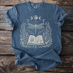 Blue t-shirt with a white graphic of a dragonfly, moon phases, and botanical elements.