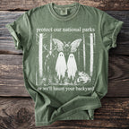 Green t-shirt with "protect our national parks or we'll haunt your backyard" text and a forest graphic.