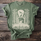 Green t-shirt with graphic of two wolves, trees, a gate, and ravens.