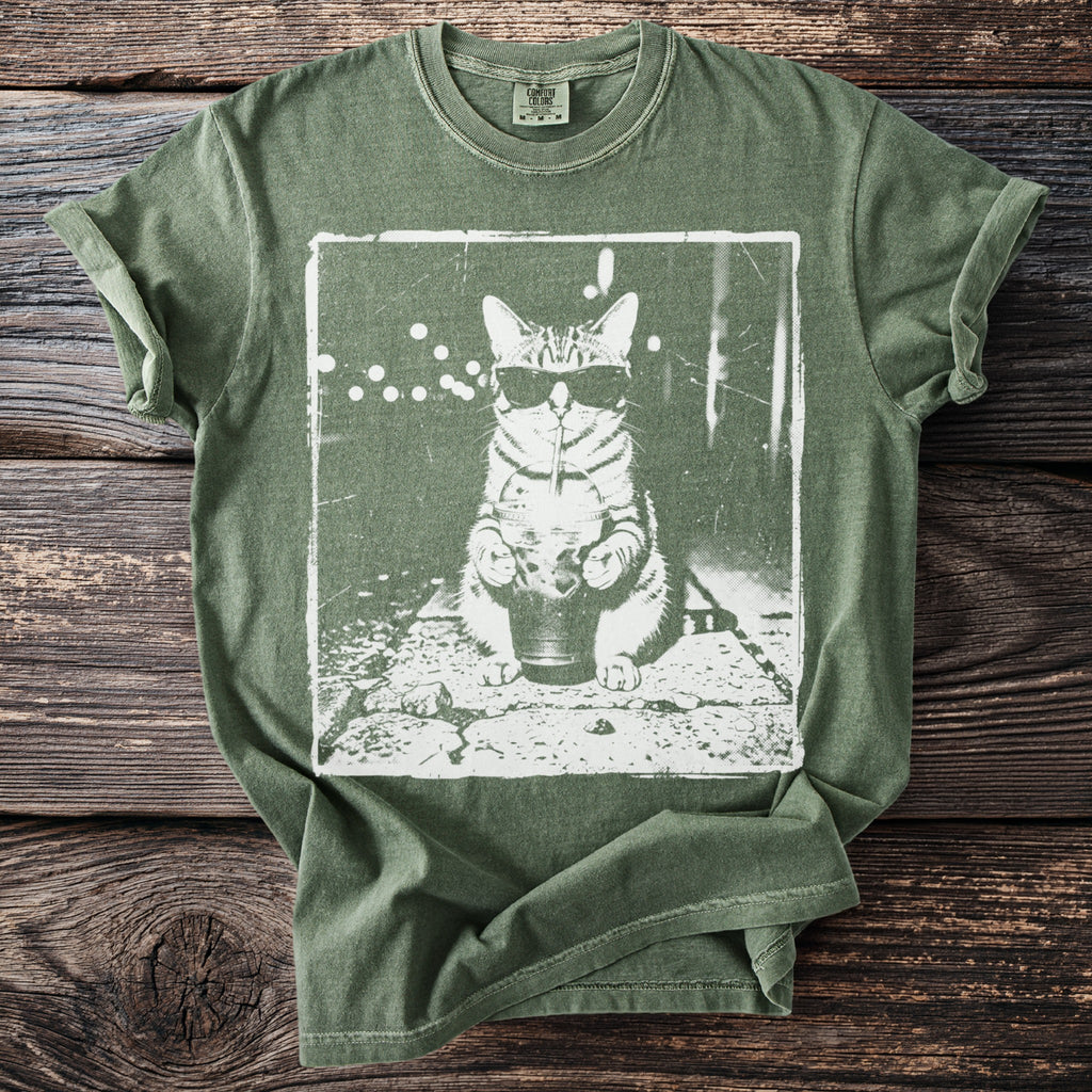 Green t-shirt with a white graphic of a cat wearing sunglasses, drinking from a cup.
