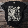 Black t-shirt with cream graphic of a weeping figure by a moonlit lake and buildings.