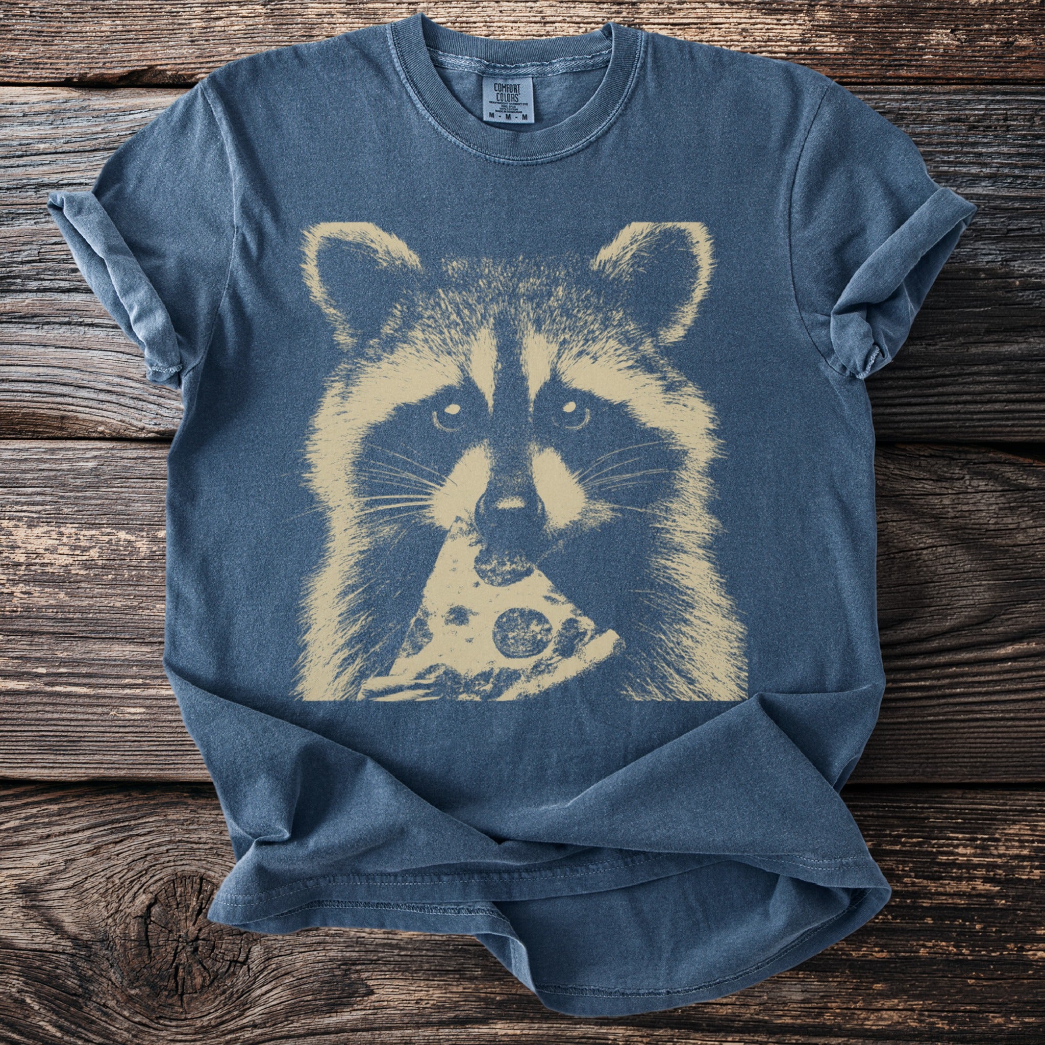 Blue t-shirt with a tan raccoon eating a slice of pizza graphic.