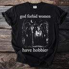 Black t-shirt with "god forbid women have hobbies" text and three witches in a forest.