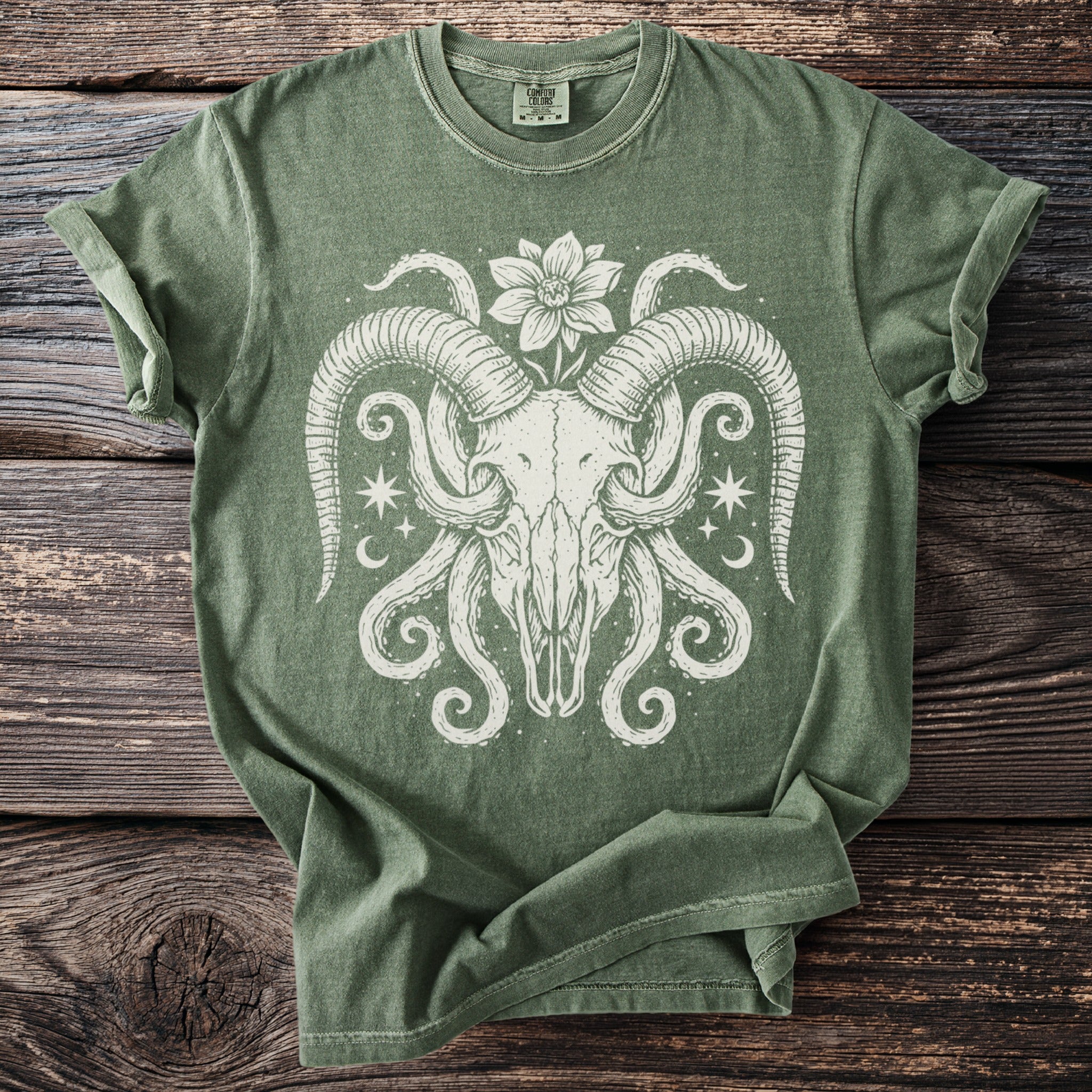 Green t-shirt with cream ram skull, flower, tentacles, moons, and stars graphic.