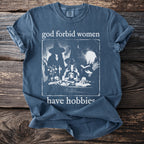 Blue t-shirt with "god forbid women have hobbies" and witch illustration.