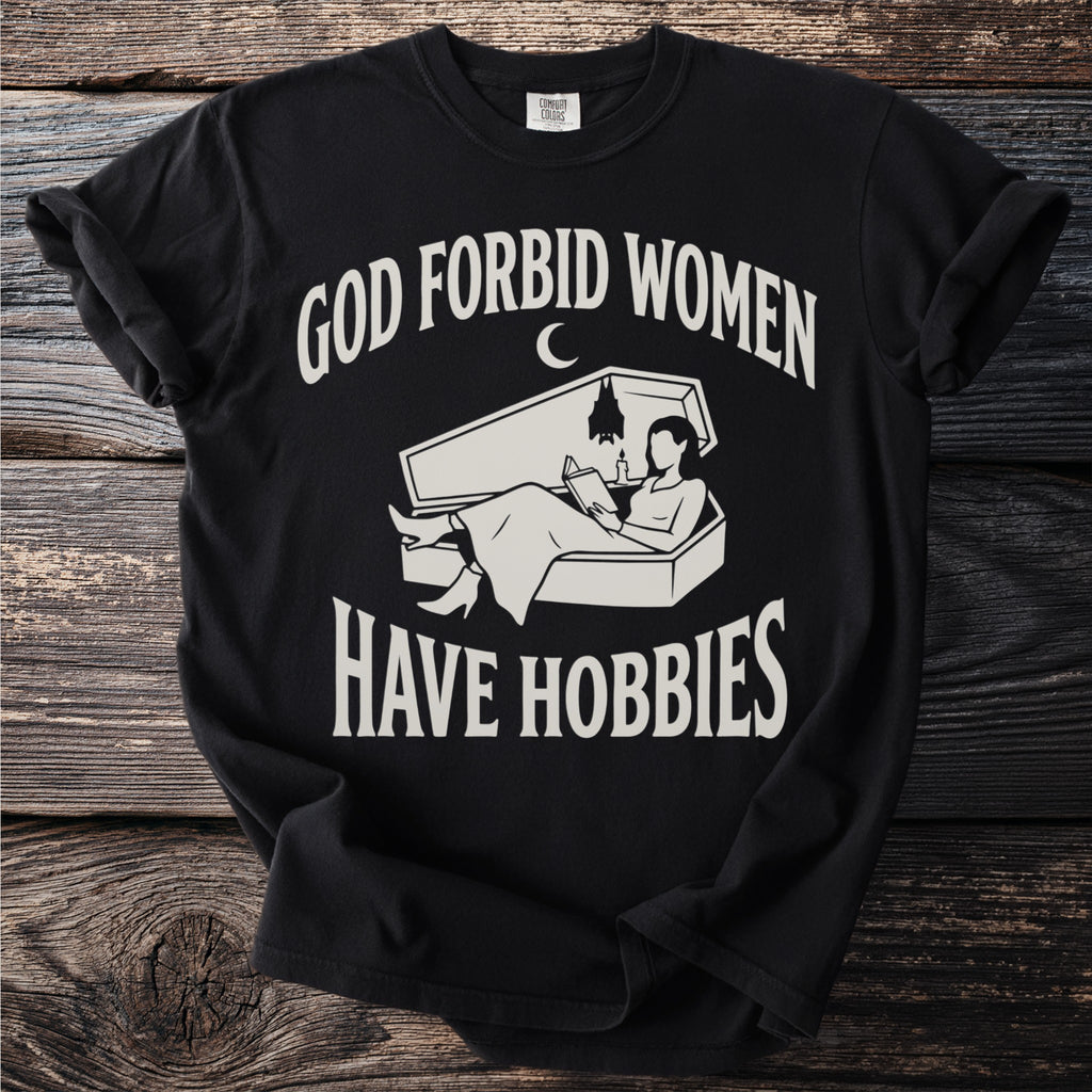 Black t-shirt with "GOD FORBID WOMEN HAVE HOBBIES" and a woman reading in a coffin.
