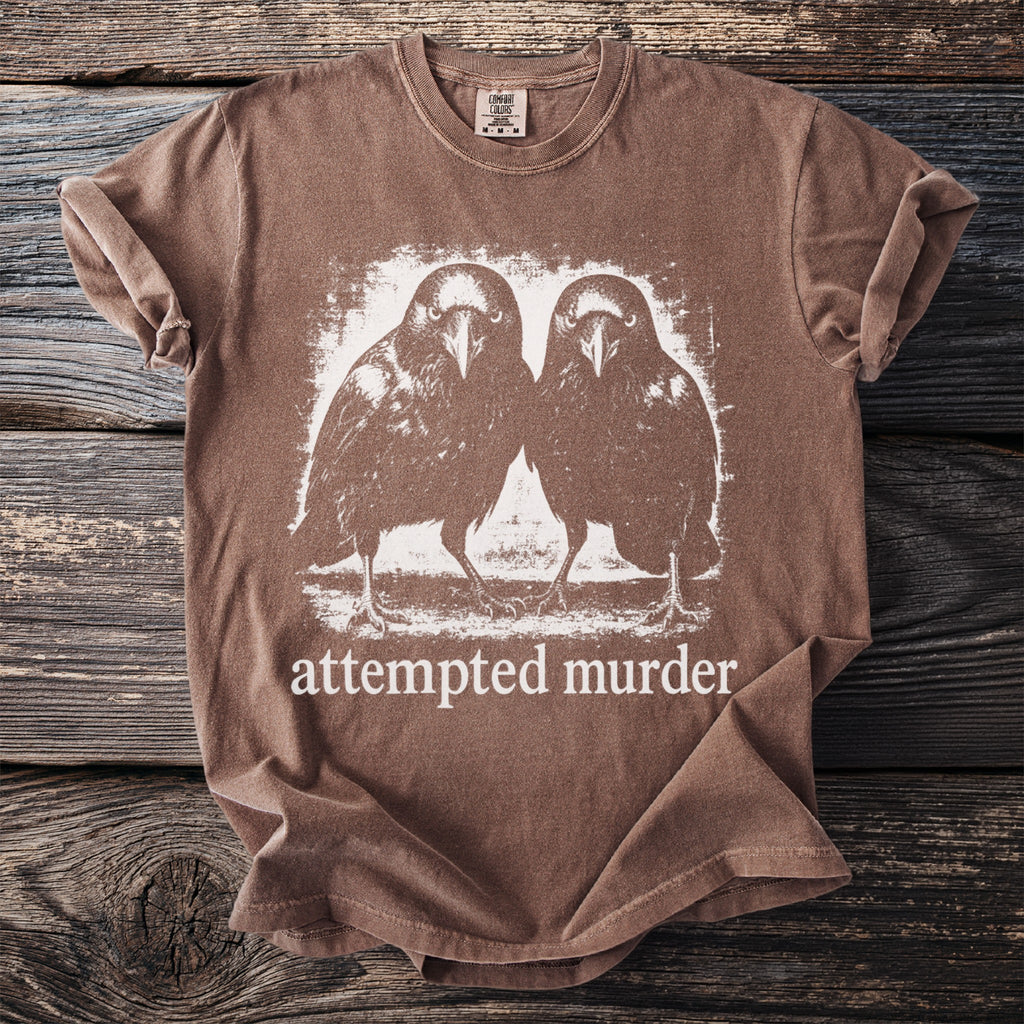 Brown t-shirt with white graphic of two crows and text "attempted murder".