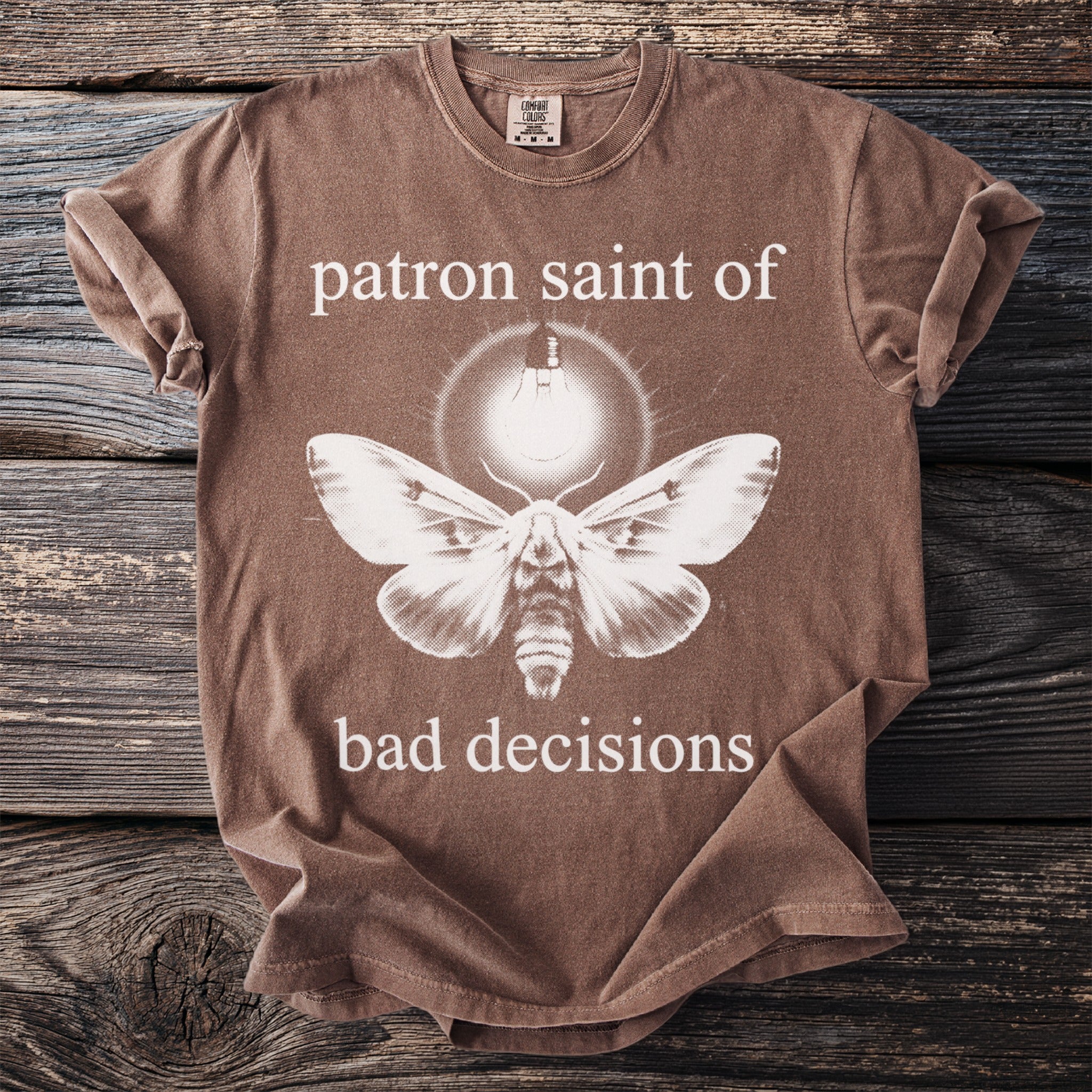 Brown t-shirt with moth design and text "patron saint of bad decisions".