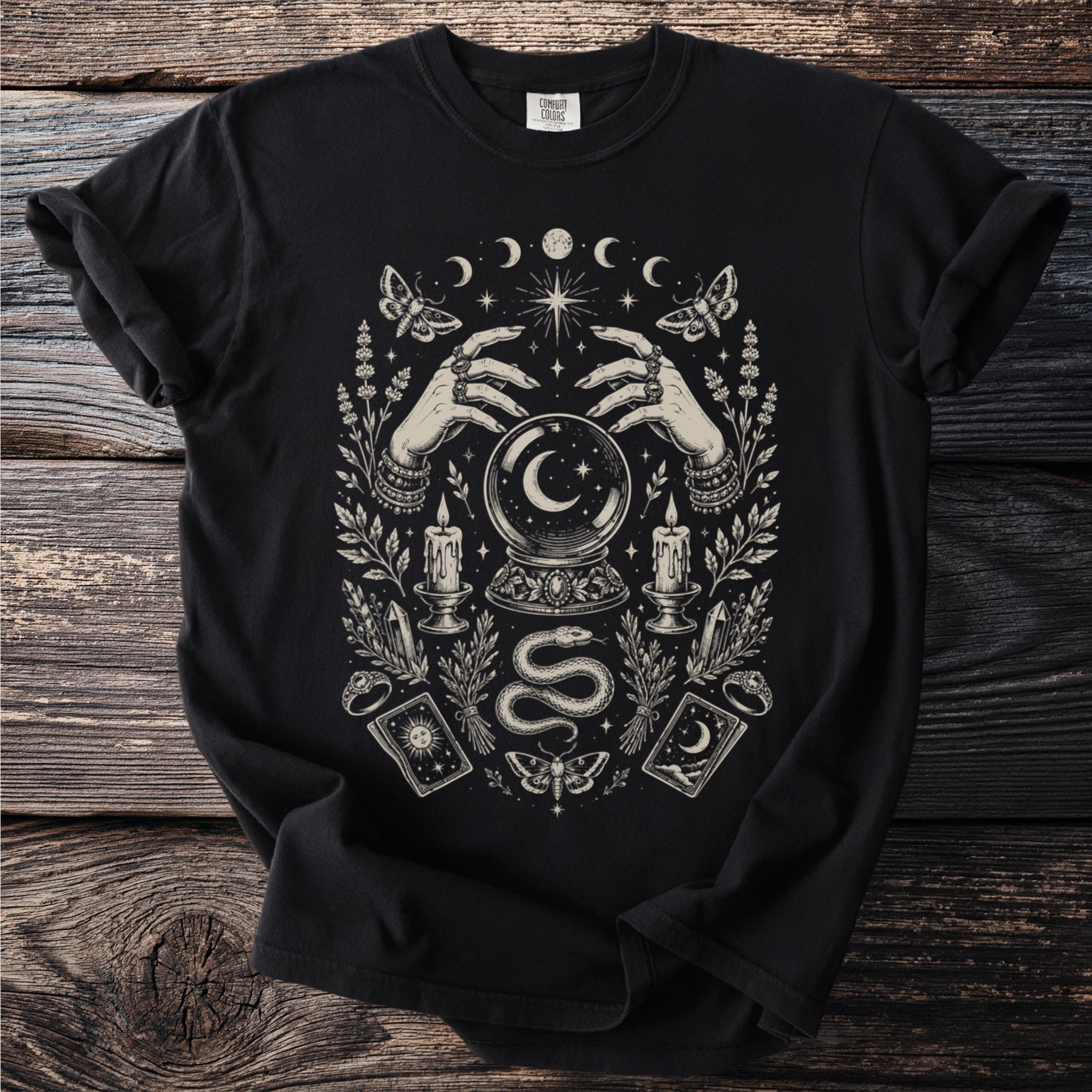 Black t-shirt with mystical occult graphic of hands, crystal ball, moon, moths, candles, and tarot cards.