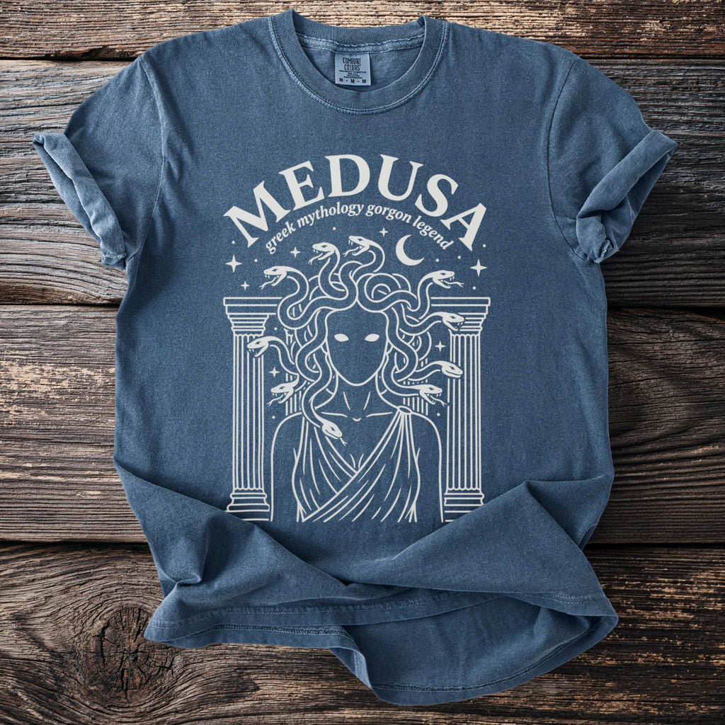 Blue t-shirt with white line art of Medusa, snakes for hair, and Greek architecture.