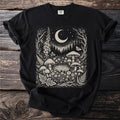 Black t-shirt with a cream-colored linocut of a forest scene featuring mushrooms, moon, and stars.