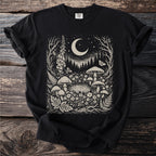 Black t-shirt with a cream-colored linocut of a forest scene featuring mushrooms, moon, and stars.