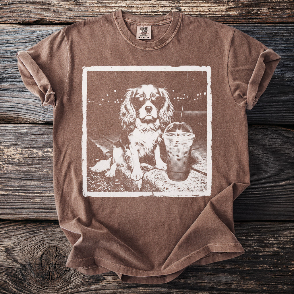 Brown t-shirt with graphic of a dog wearing sunglasses next to a to-go iced coffee.