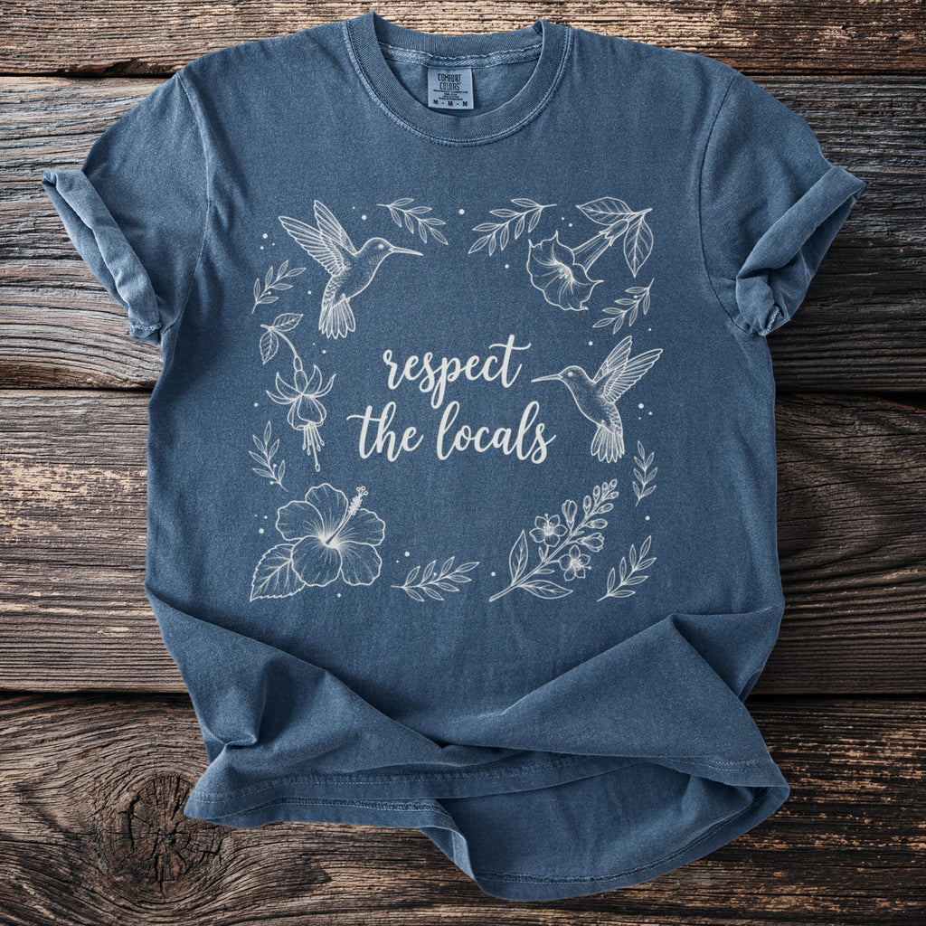 Blue t-shirt with white line art of hummingbirds and flowers, saying "respect the locals".