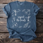 Blue t-shirt with white line art of hummingbirds and flowers, saying "respect the locals".