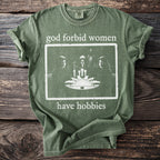 Green t-shirt with text and image of three figures around a table with candles.