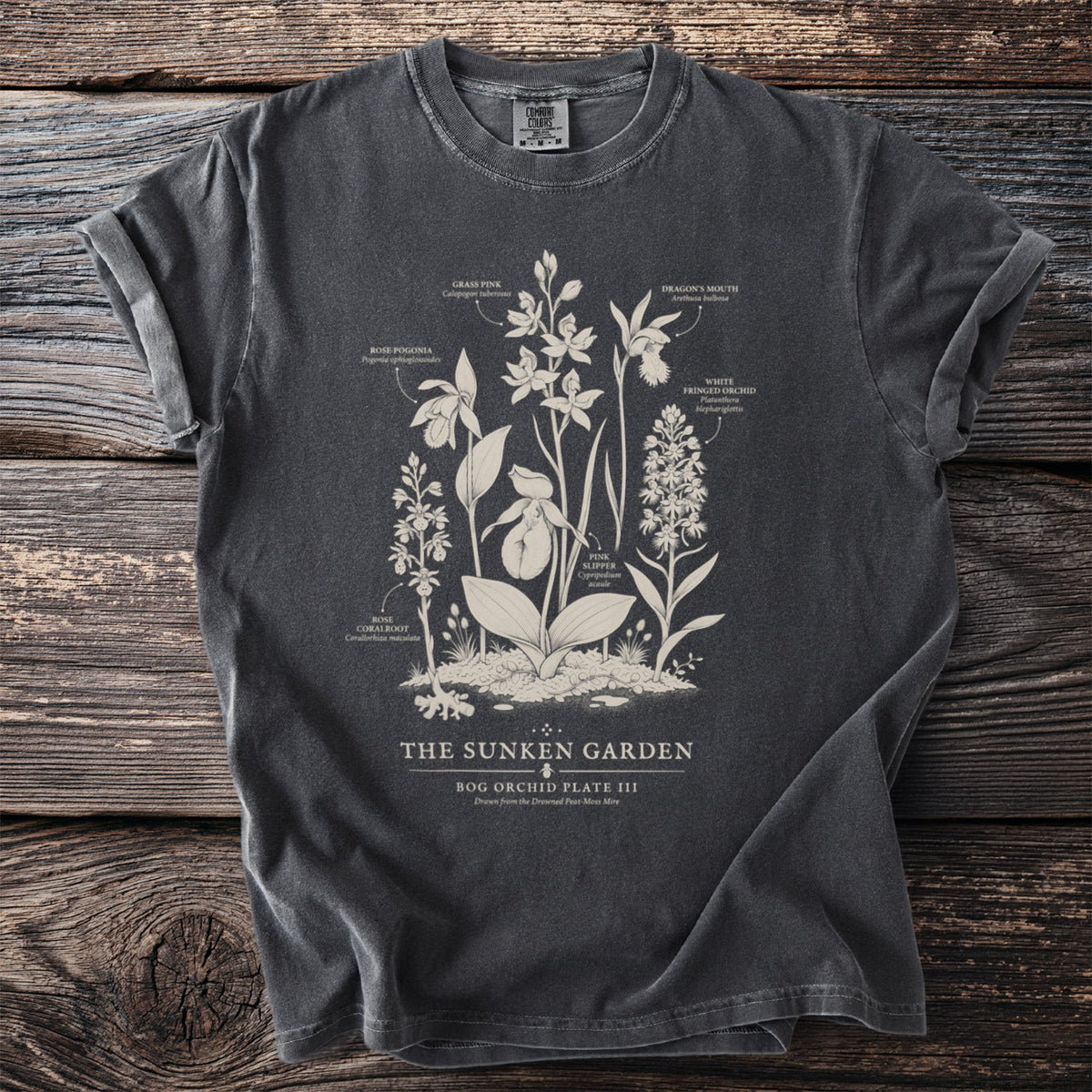 Dark t-shirt with white botanical illustration of orchids and text "The Sunken Garden Bog Orchid Plate III".