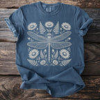 Blue t-shirt with a detailed white illustration of a dragonfly surrounded by flowers and ferns.