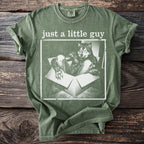 Green t-shirt with a graphic of a wolf in a box and text "just a little guy".