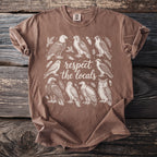 Brown t-shirt with a design of various birds and the text "respect the locals".