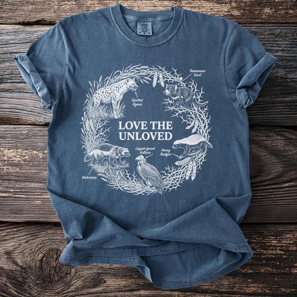 Blue t-shirt with white line art of "Love The Unloved" animals in a wreath.