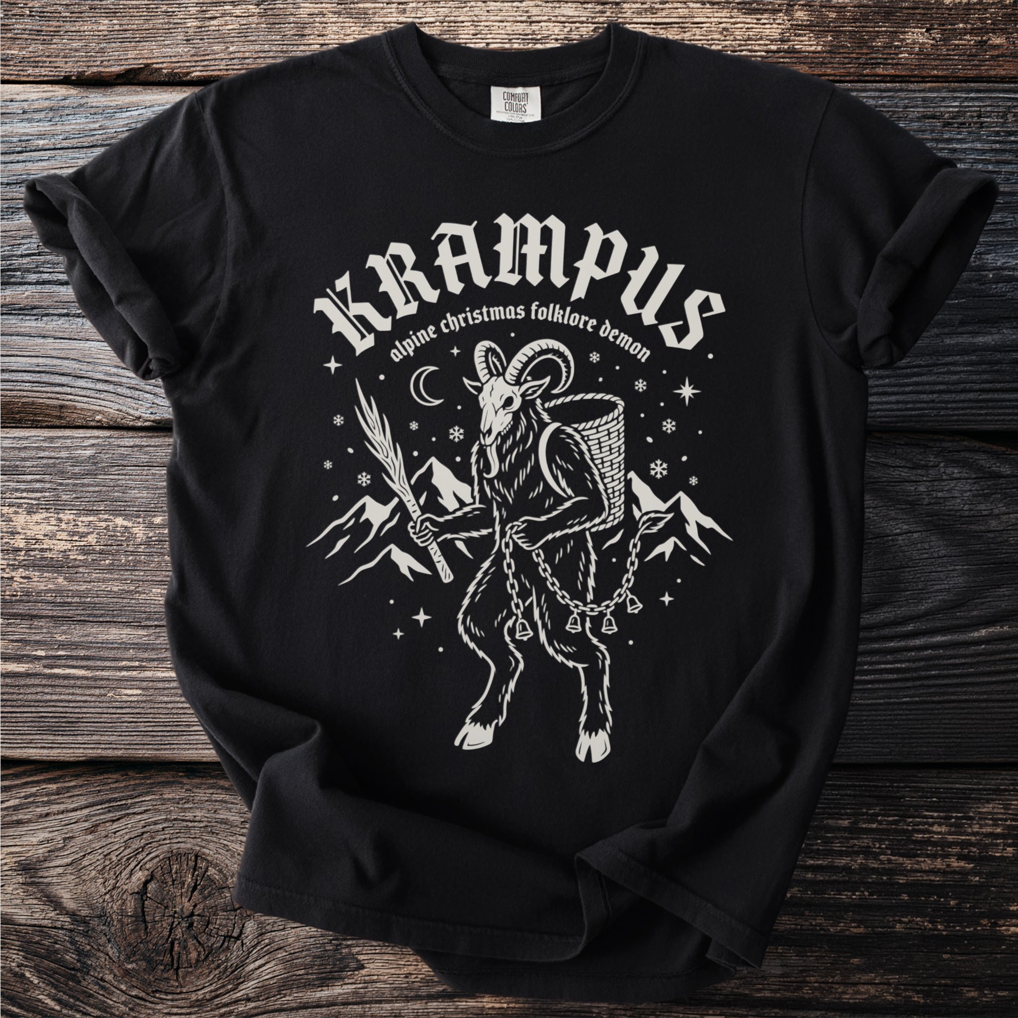 Black t-shirt with Krampus, alpine folklore demon, mountain, and snowflake design.