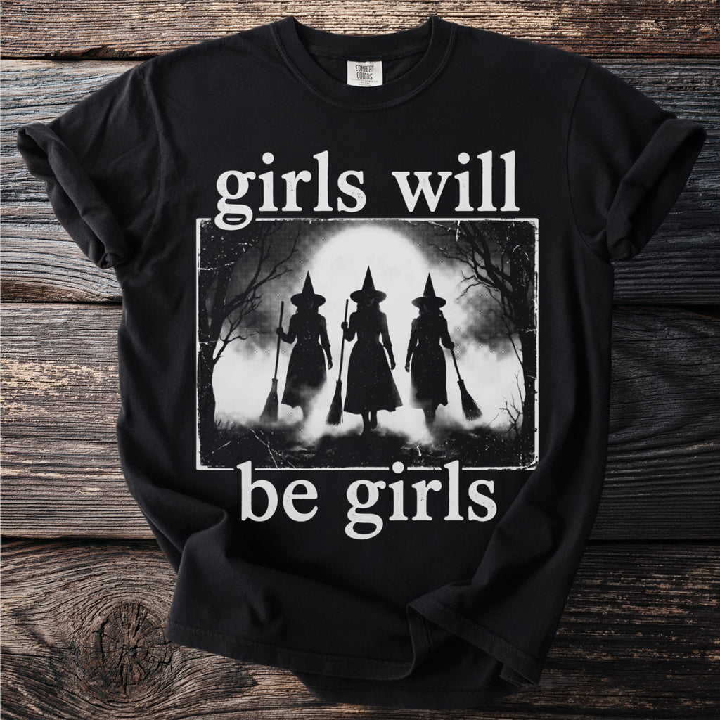Black t-shirt with "girls will be girls" text and a graphic of three witches with brooms.