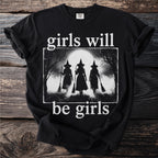 Black t-shirt with "girls will be girls" text and a graphic of three witches with brooms.