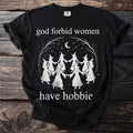 Black t-shirt with white graphic of witches dancing under a moon and stars, reading "god forbid women have hobbie".