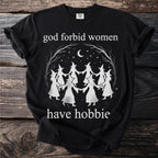 Black t-shirt with white graphic of witches dancing under a moon and stars, reading "god forbid women have hobbie".