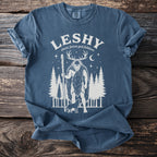 Blue t-shirt with graphic of Leshy, Slavic forest god, folklore, trees, and wolf.