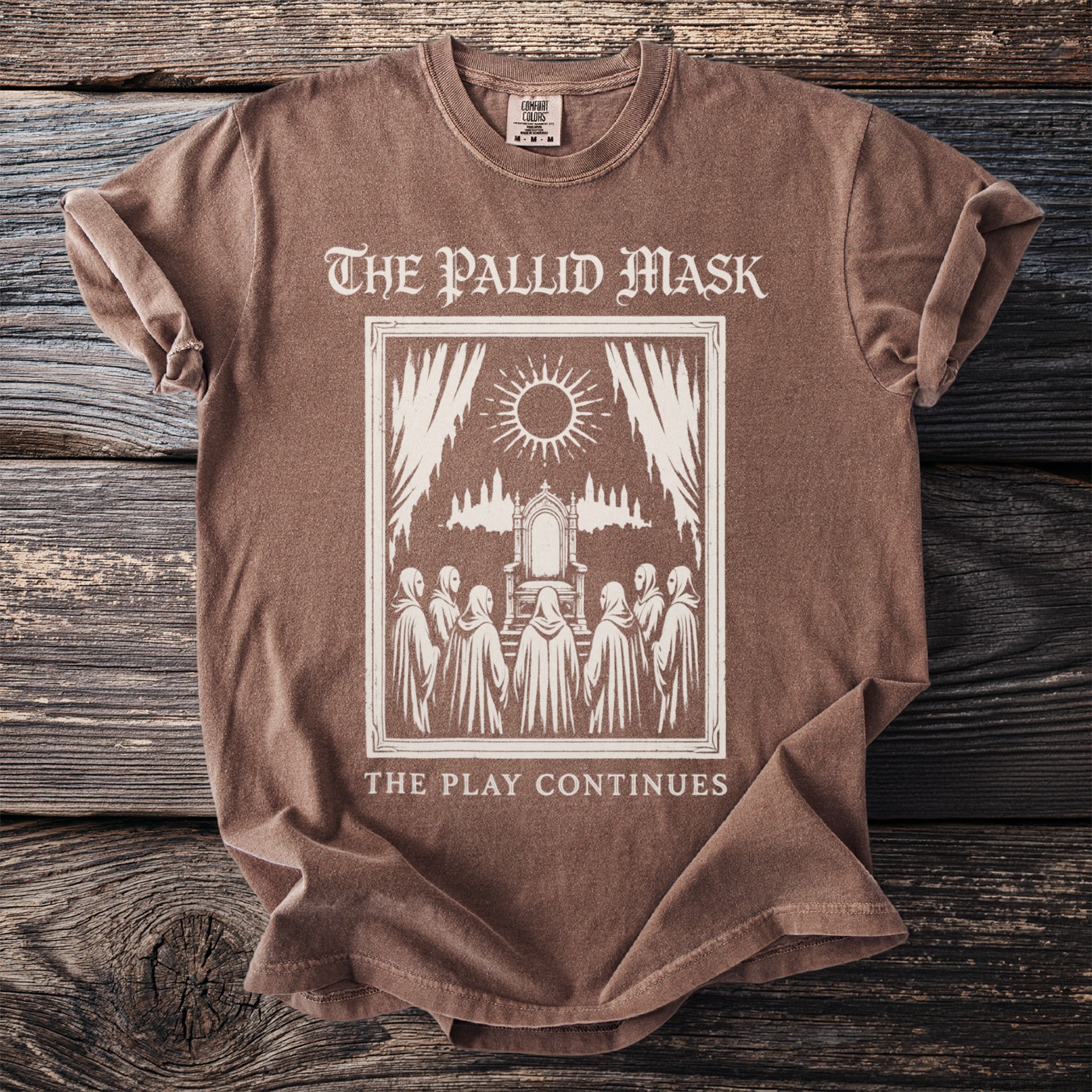 Brown t-shirt with a graphic of robed figures around a throne, "The Pallid Mask" and "The Play Continues".
