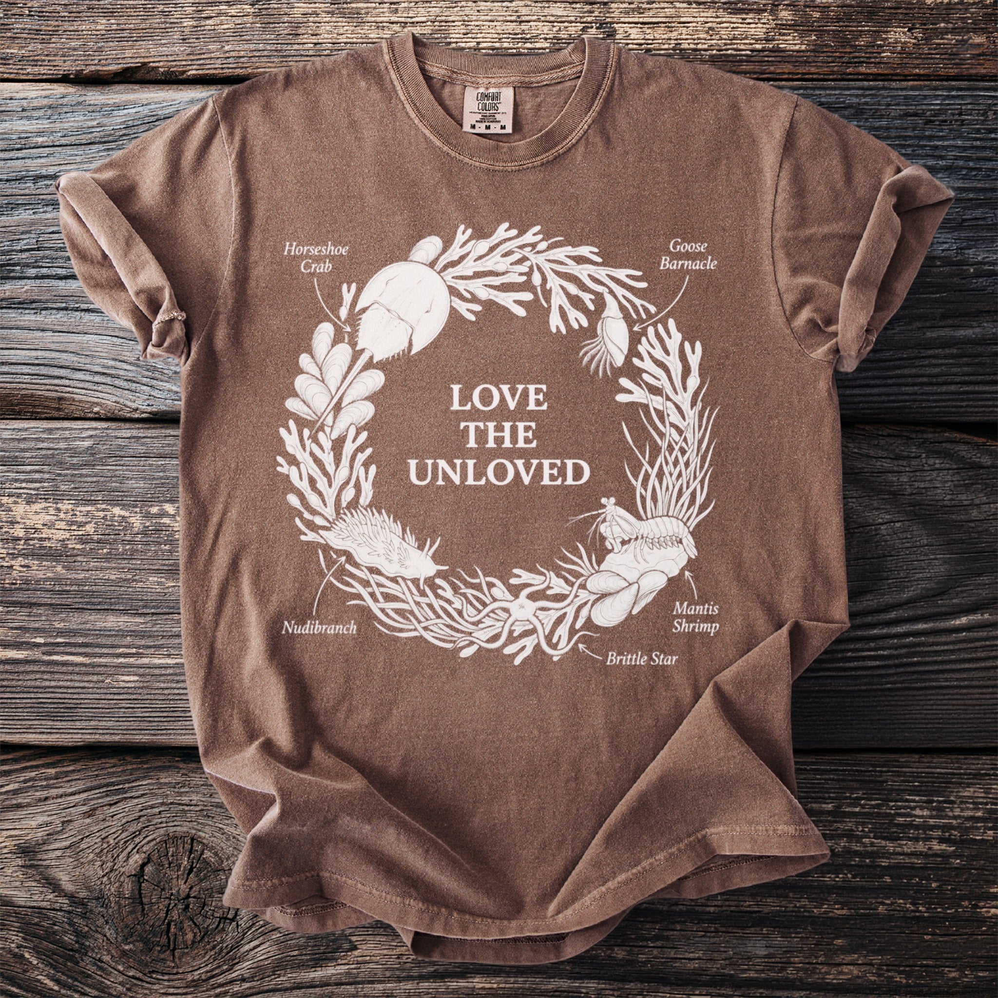 Brown t-shirt with a white circular graphic of marine life and text "LOVE THE UNLOVED".