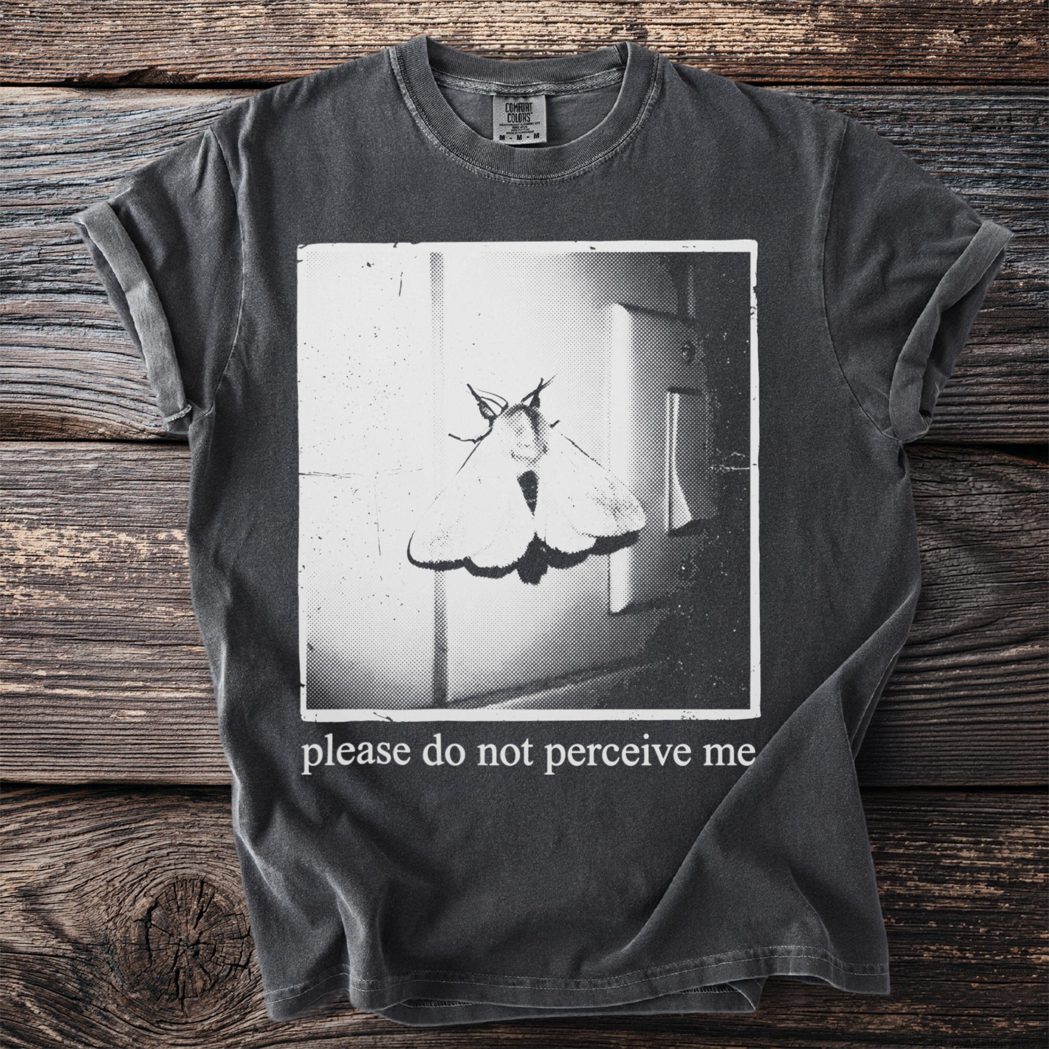 Dark t-shirt with a moth graphic and "please do not perceive me" text.