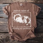 Brown t-shirt with opossum graphic and text "patron saint of avoiding my problems".