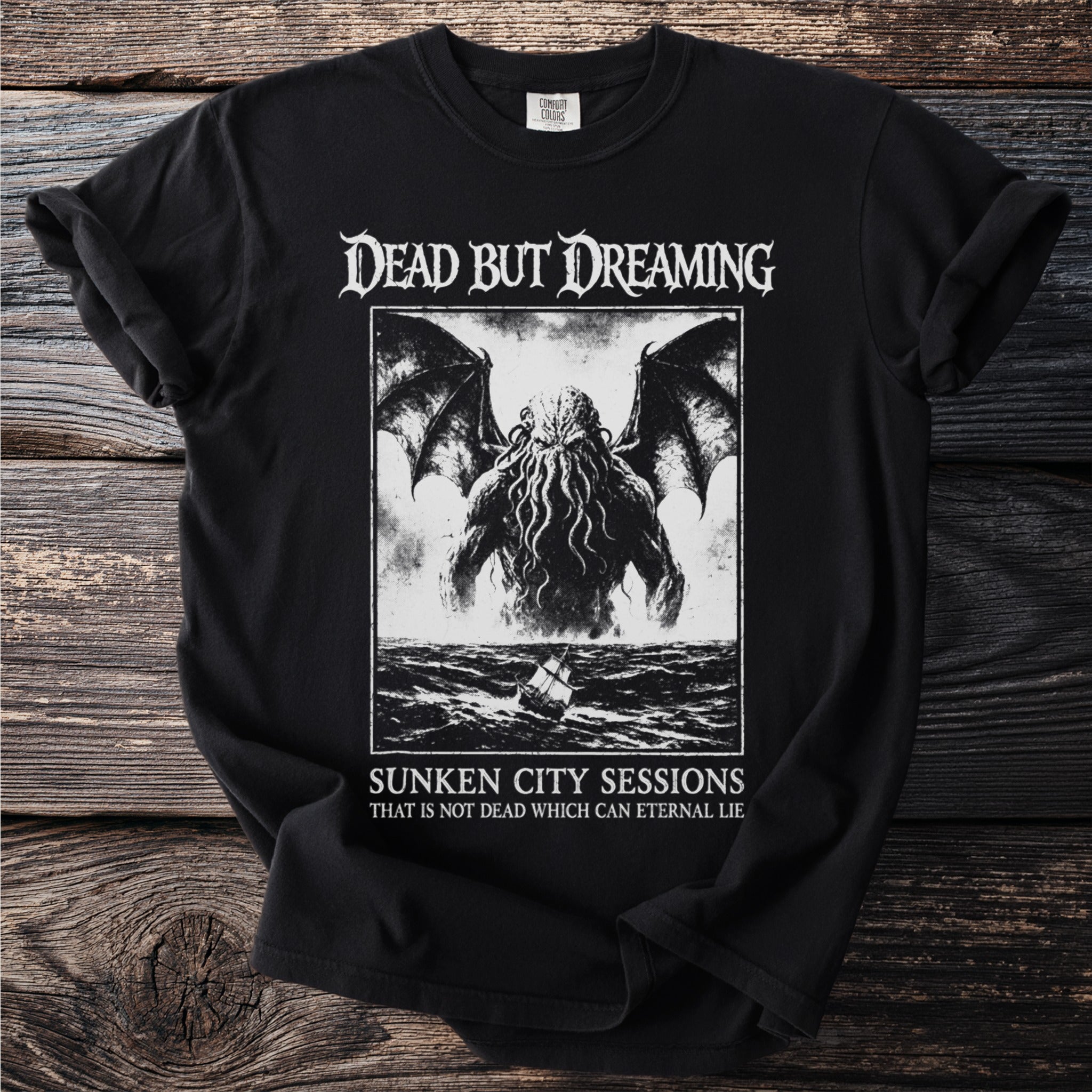 Black t-shirt with "Dead But Dreaming" graphic of a tentacled creature and a ship.