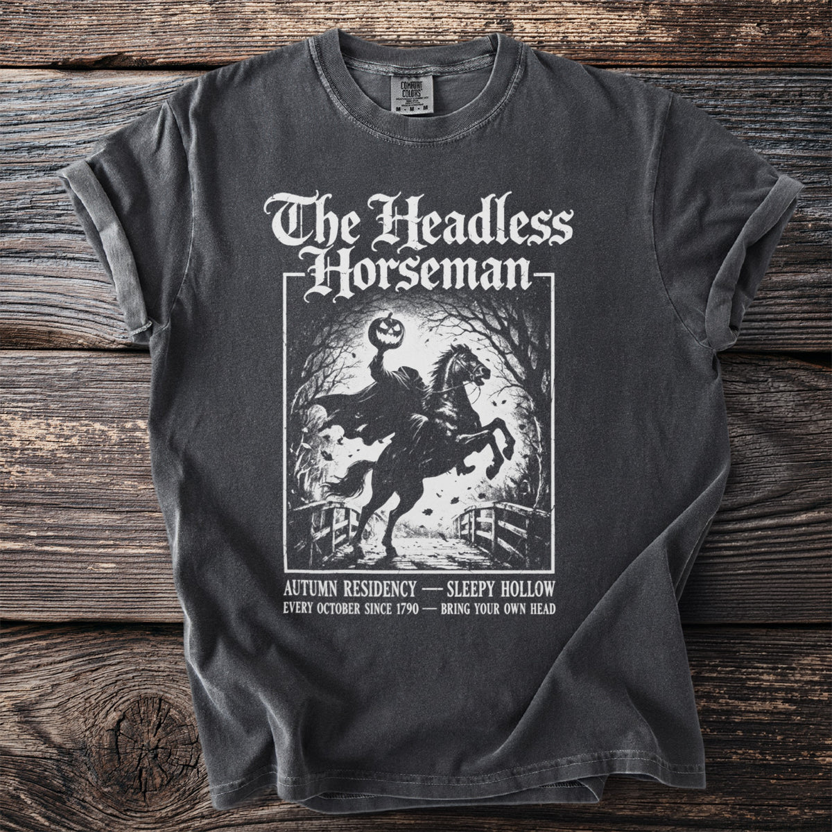 T-shirt graphic: Headless Horseman on horseback with pumpkin, autumn text.
