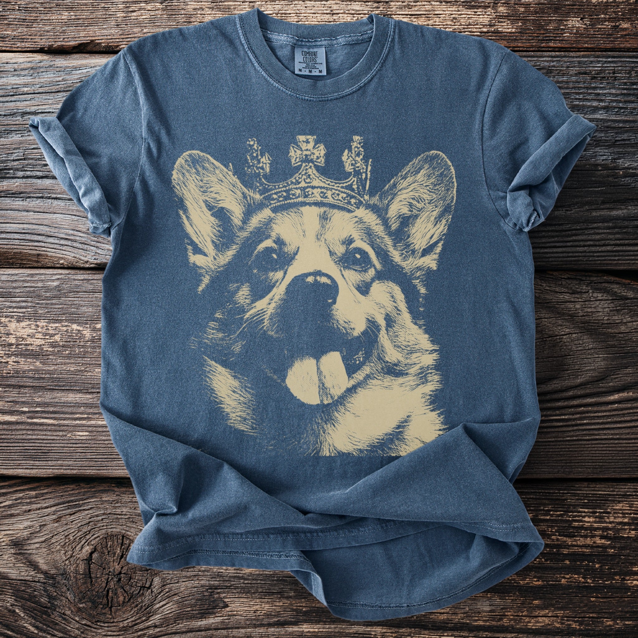 Blue t-shirt with a beige graphic of a corgi wearing a crown.