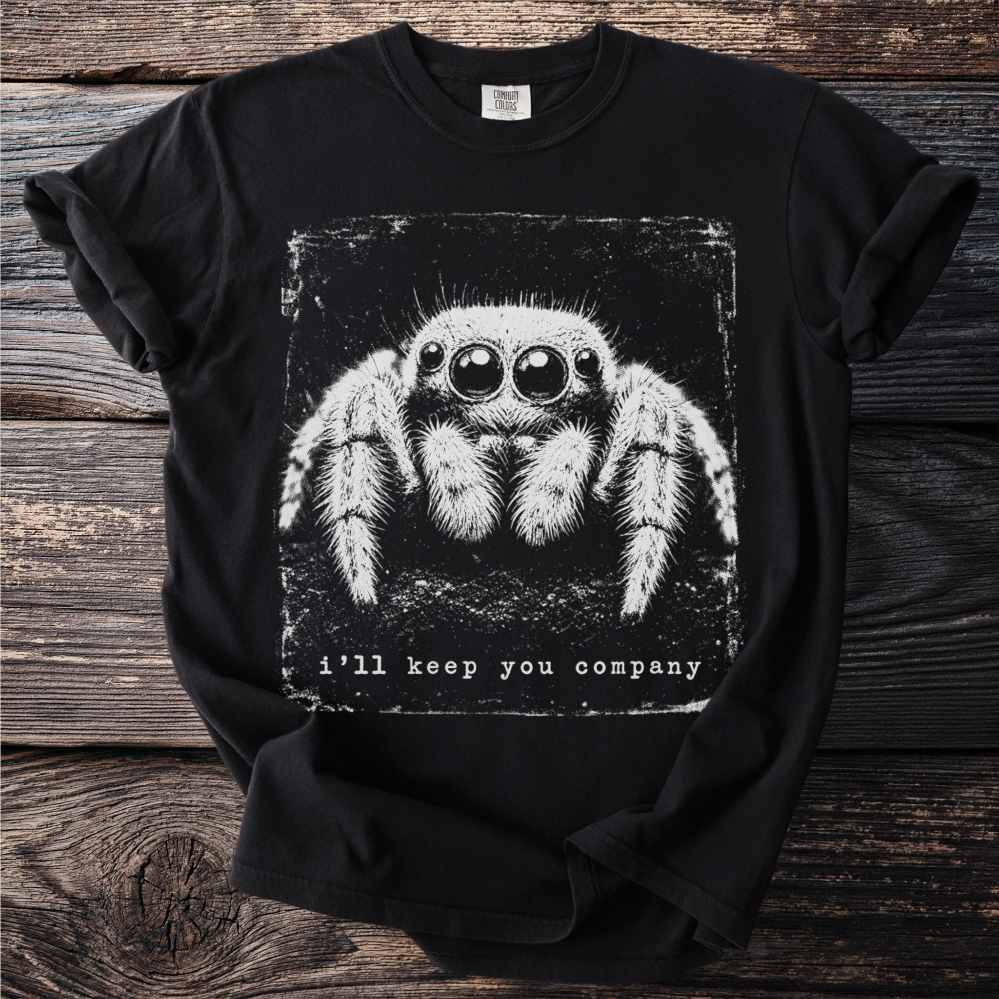Black t-shirt with a close-up white graphic of a furry spider and text that reads "i'll keep you company".