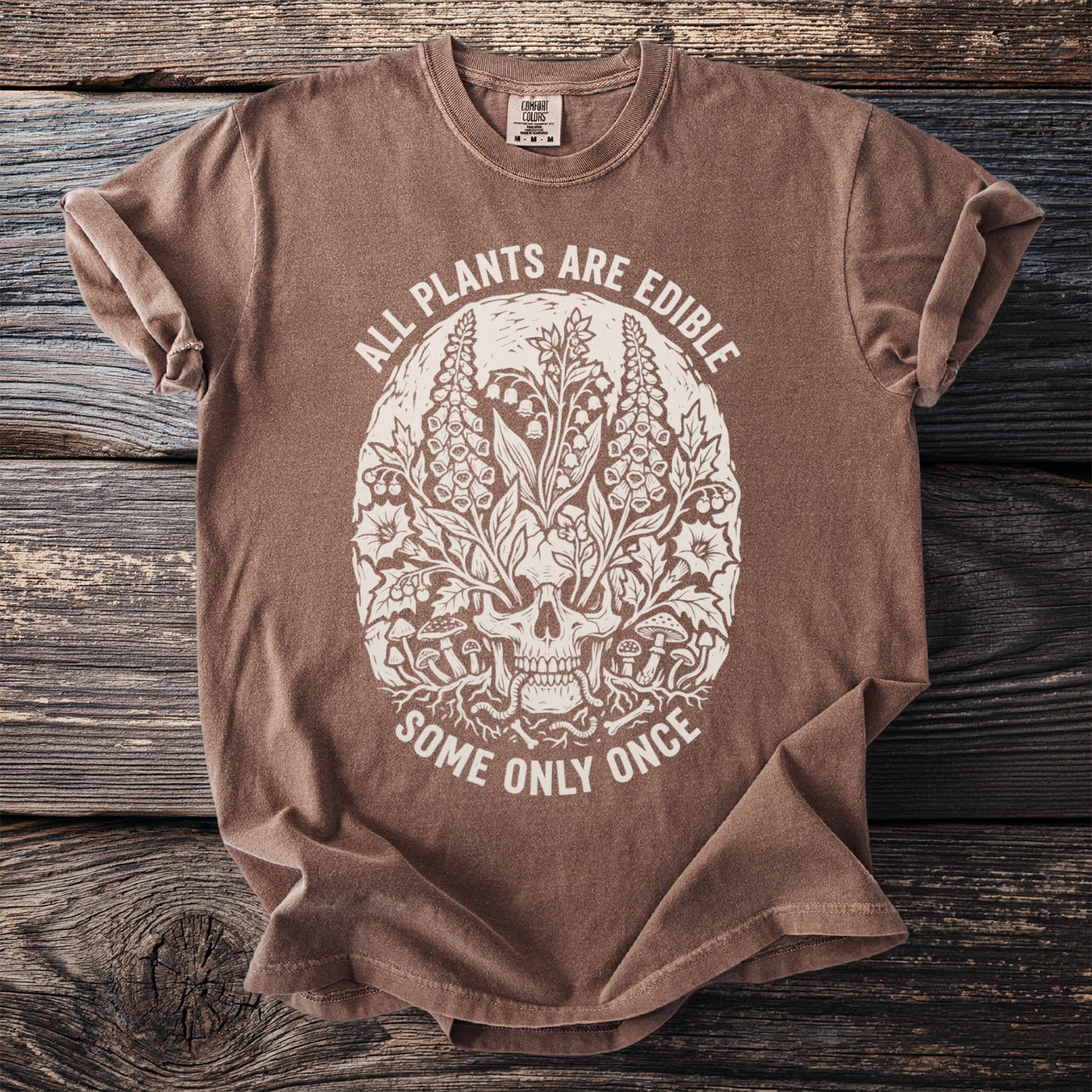 Brown shirt with skull and plants design, "All plants are edible, some only once"