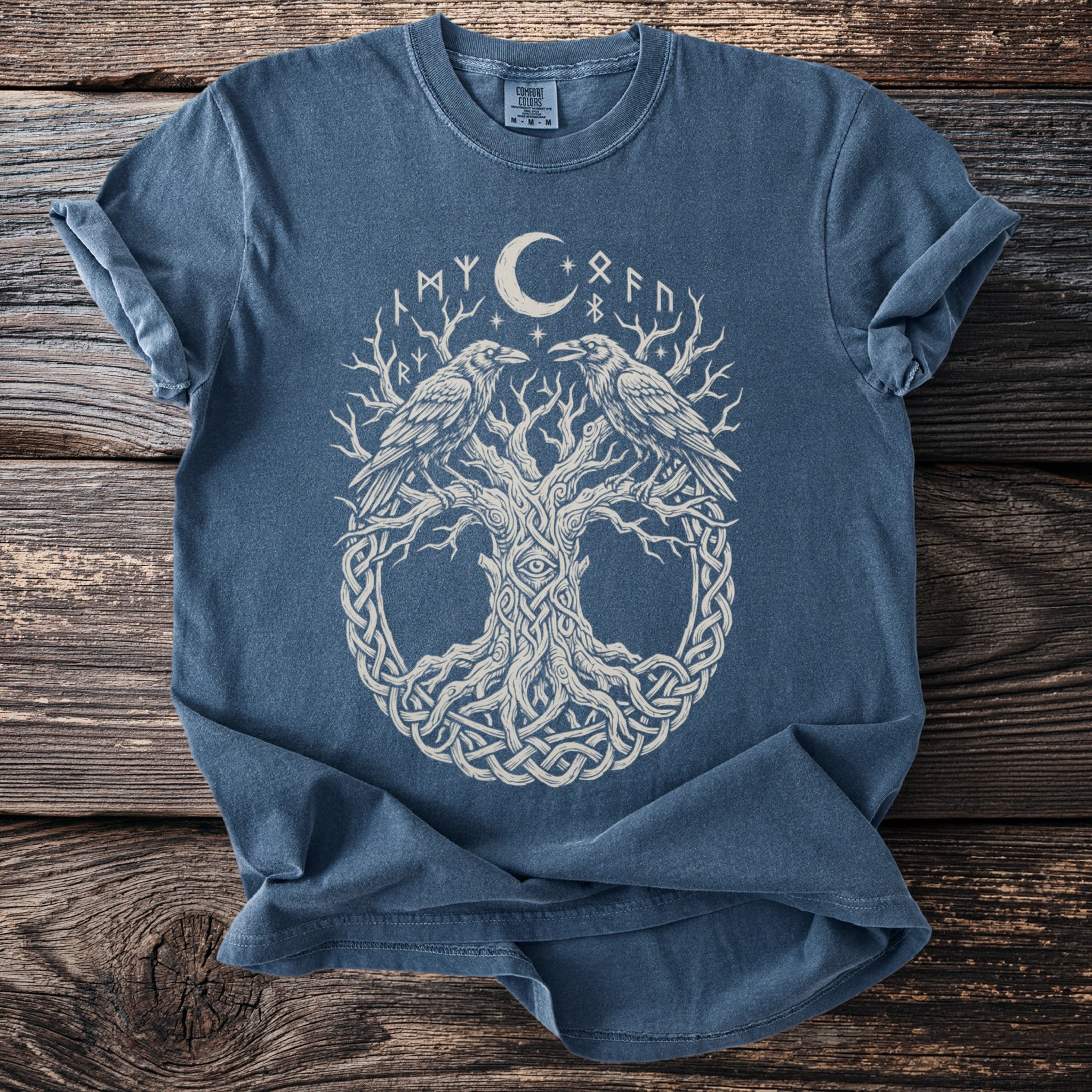 Blue t-shirt with a white graphic of a tree, two ravens, moon, and runes.
