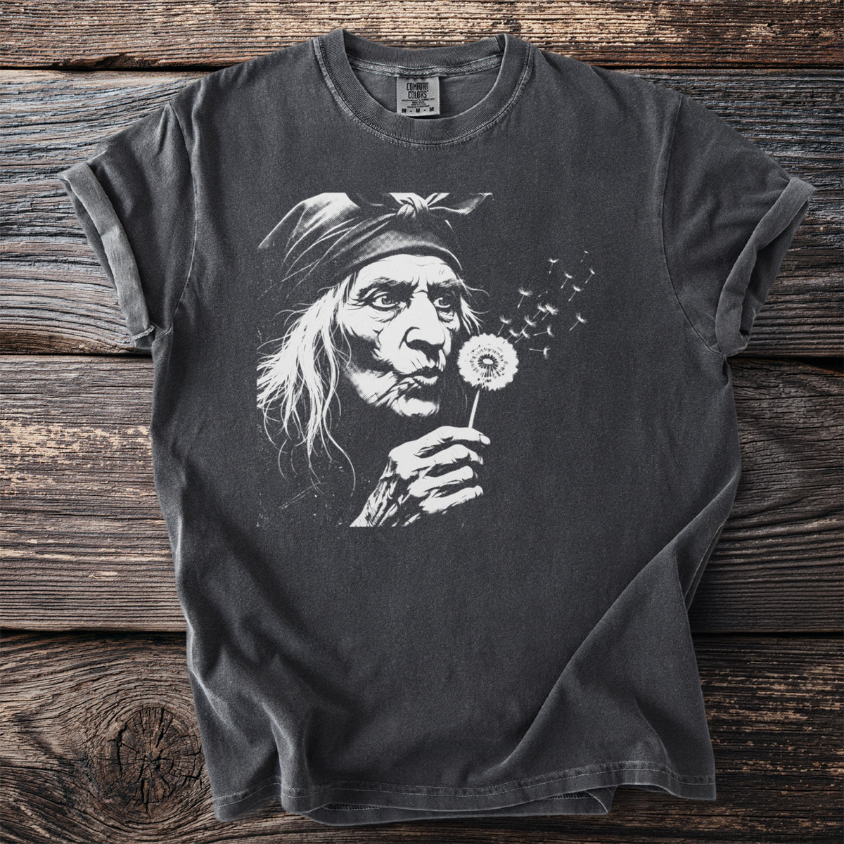 Dark gray t-shirt with graphic of an elder woman blowing a dandelion.