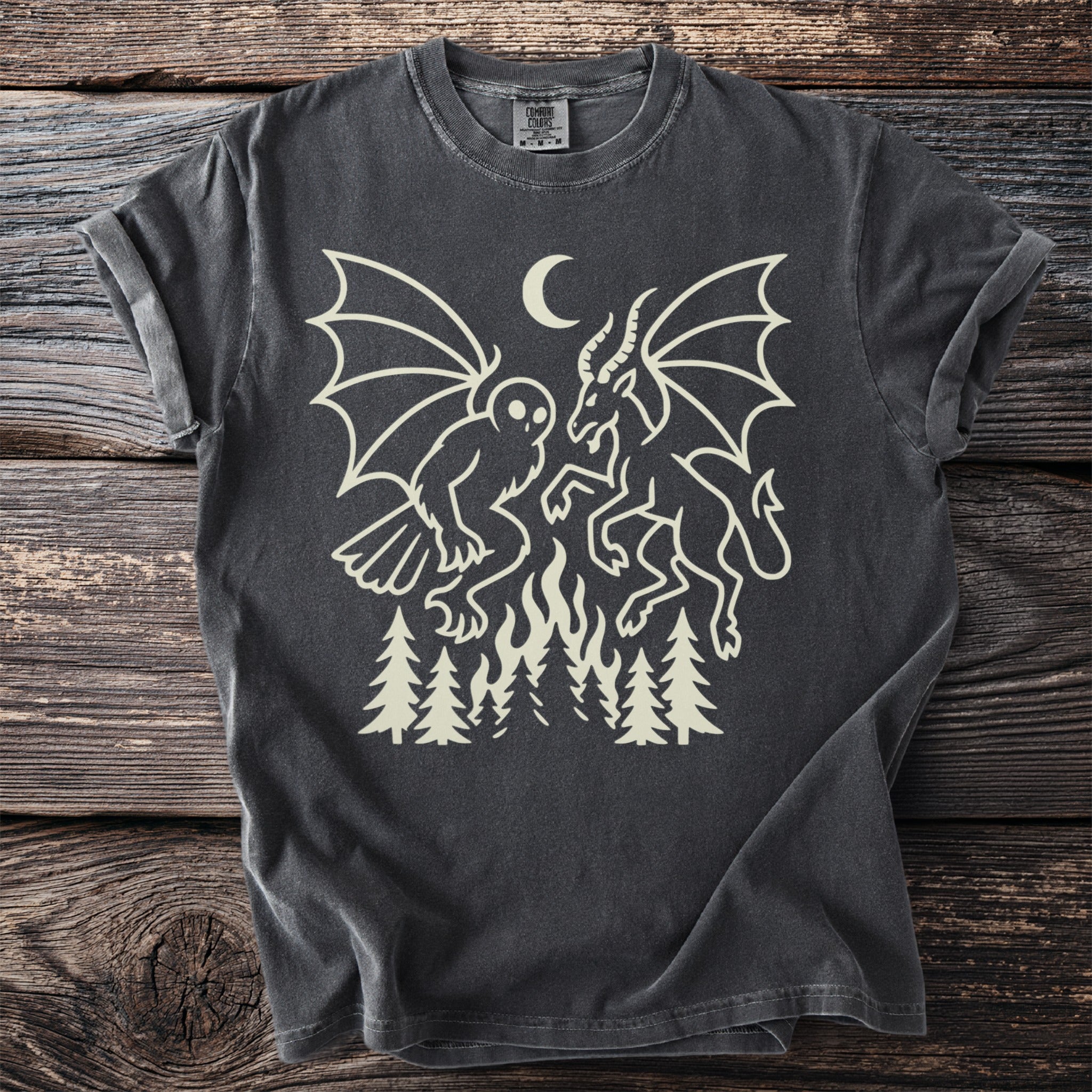 Dark gray t-shirt with cream graphic of mythical creatures, moon, fire, and trees.