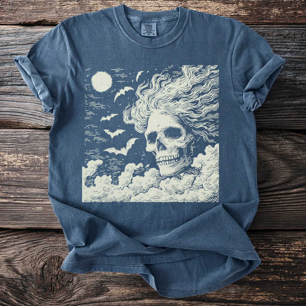 T-shirt with a cream-colored skull, bats, and moon graphic on dark blue fabric.