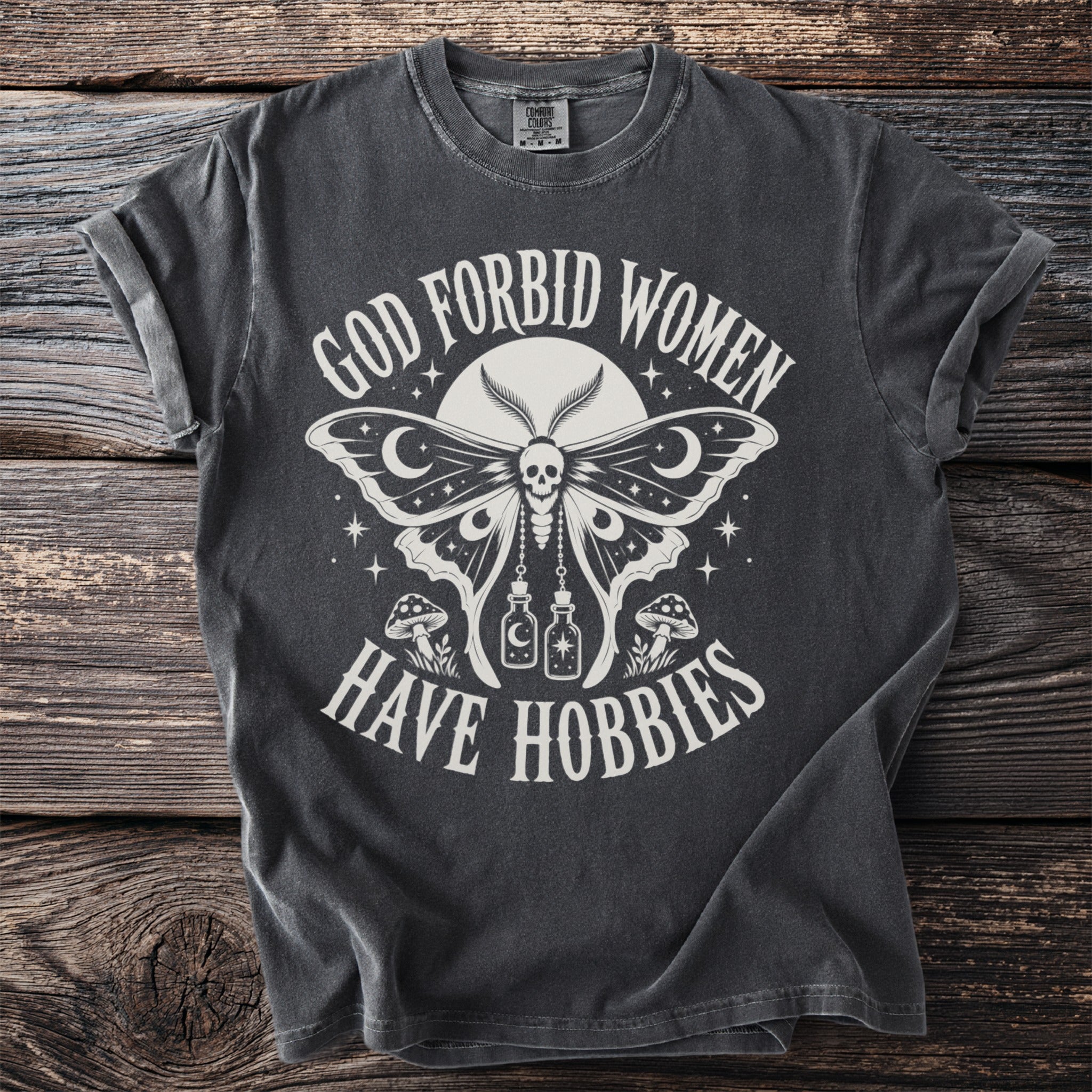 Dark grey t-shirt with moth graphic and text "GOD FORBID WOMEN HAVE HOBBIES".