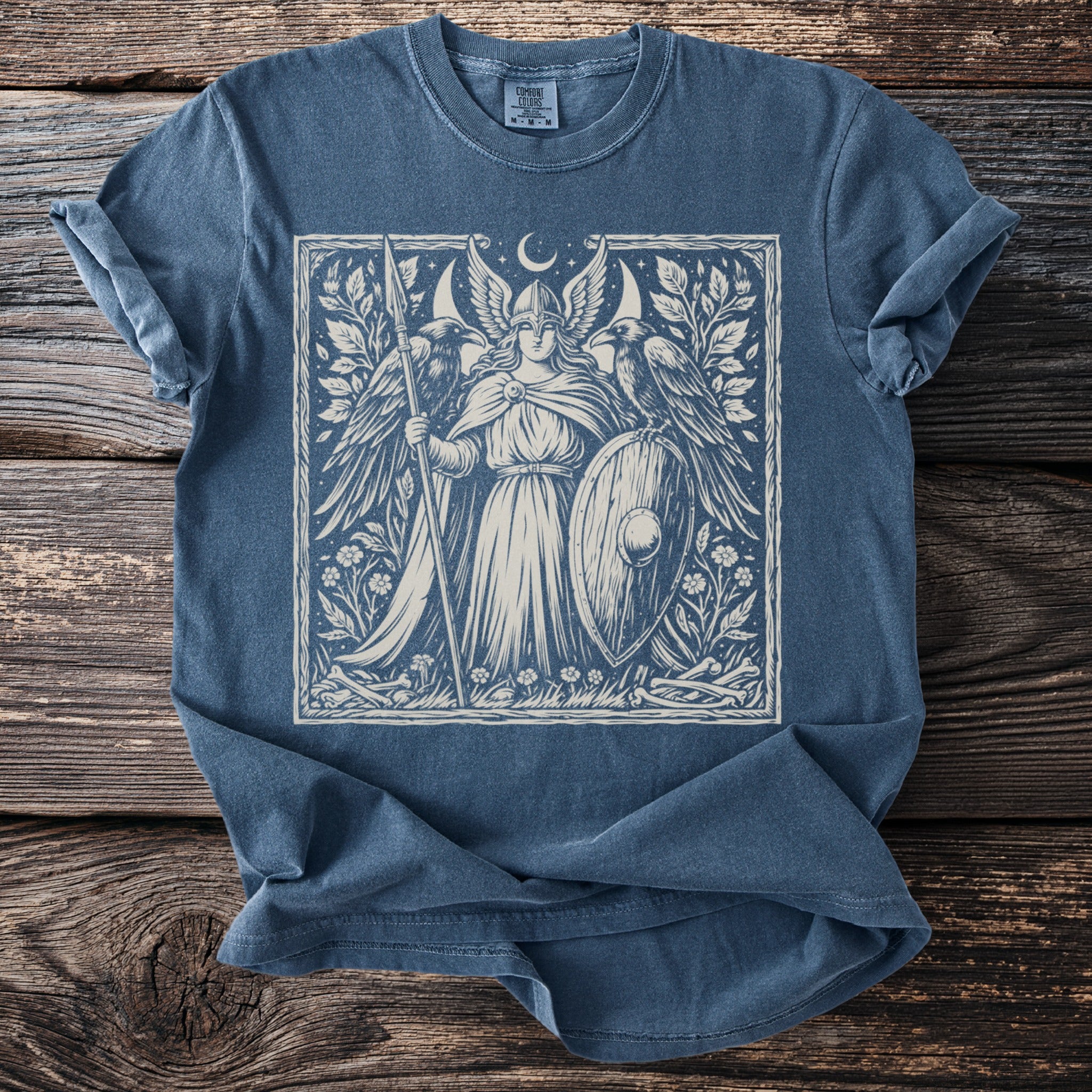 Blue t-shirt with a white ink linocut-style print of a winged warrior with a shield and spear.